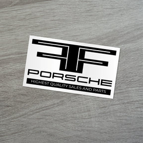 Porsche car dealership sticker showcasing highest quality sales and parts on a wooden surface.