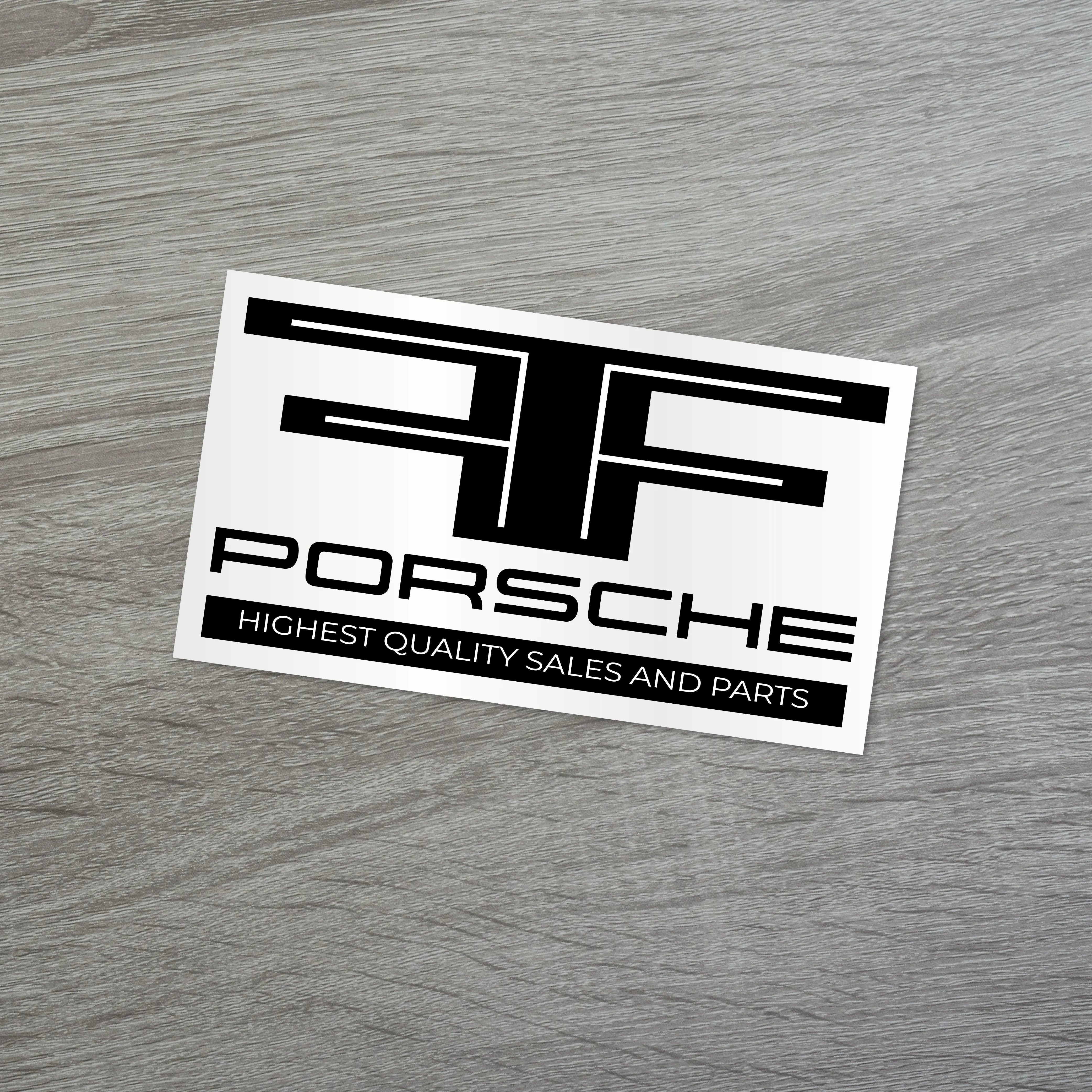 Porsche car dealership sticker showcasing highest quality sales and parts on a wooden surface.