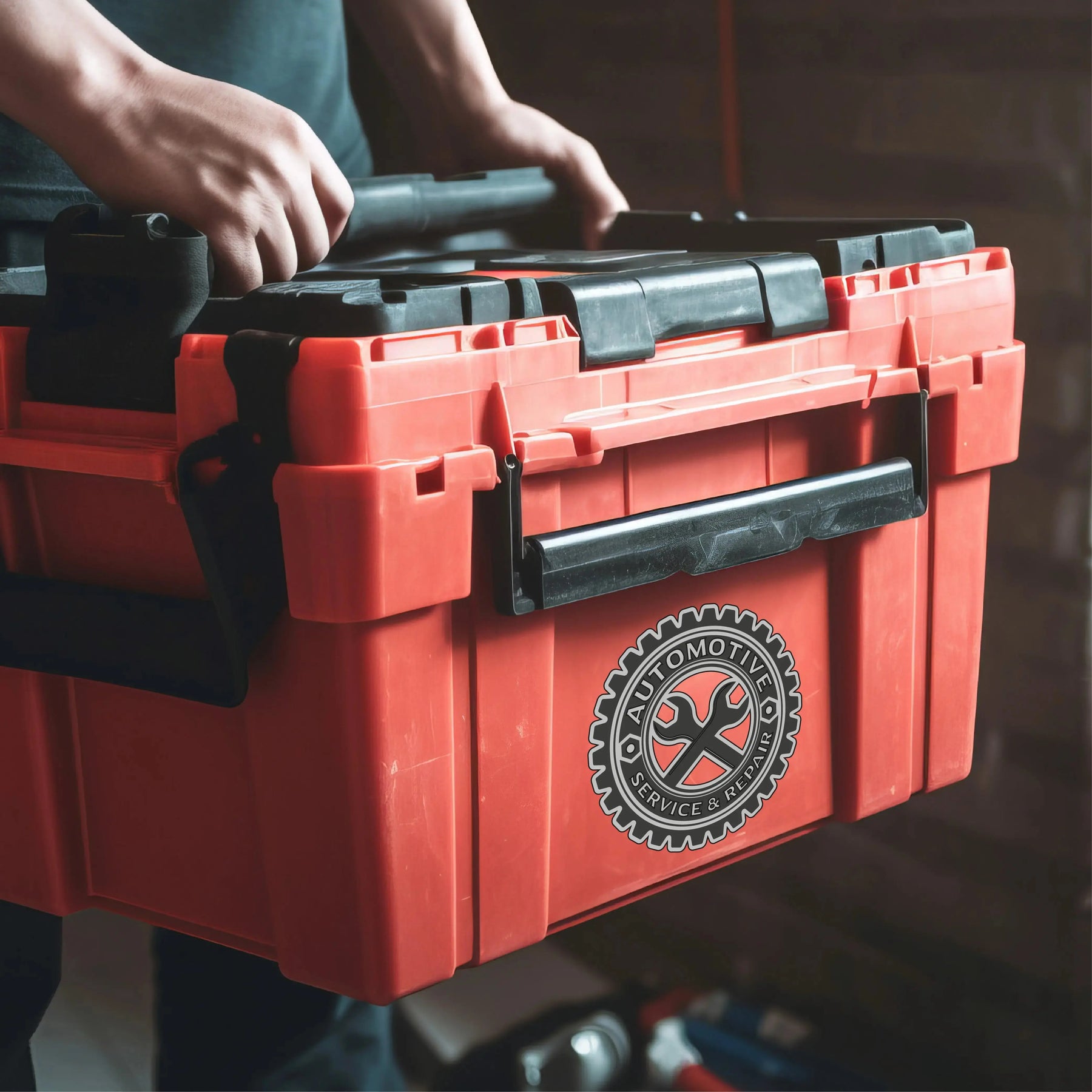 Person holding a heavy-duty red tool box with a logo on it, ideal for tough work environments.